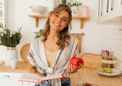 mlada devojka sa osmehom na licu drzi crvenu papriku bogatu vitaminom c u ruci